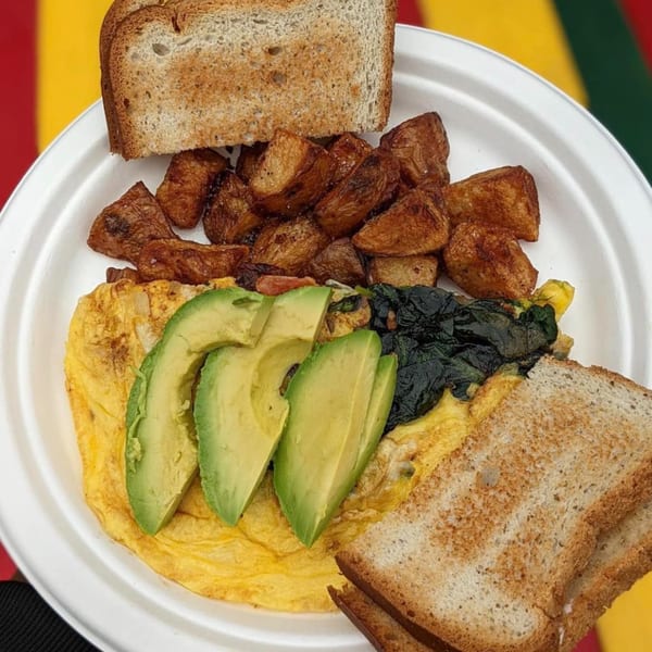 A Stella Blue Bistro breakfast plate with an omelet, avocado slices, roasted potatoes, and toast.
